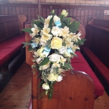 Vanilla Sky rose, alstroemeria and lisianthus pew end with coordinating foliage enhanced with duck egg blue ribbons.