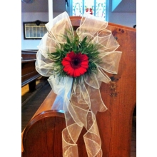 Gerbera pew end with coordinating foliage enhanced with cream voile.