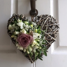 Memory Lane rose, freesia, spray rose, lisianthus, veronica and gypsophila with coordinating foliage on a rustic heart.