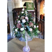 Church pedestal containing Sweet Avalanche and Amnesia rose, hydrangea, chrysanthemum bloom, antirrhinum, lisianthus and astrantia with coordinating foliage.