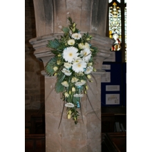 Gerbera and lisianthus column design with coordinating foliage enhanced with teal bows.